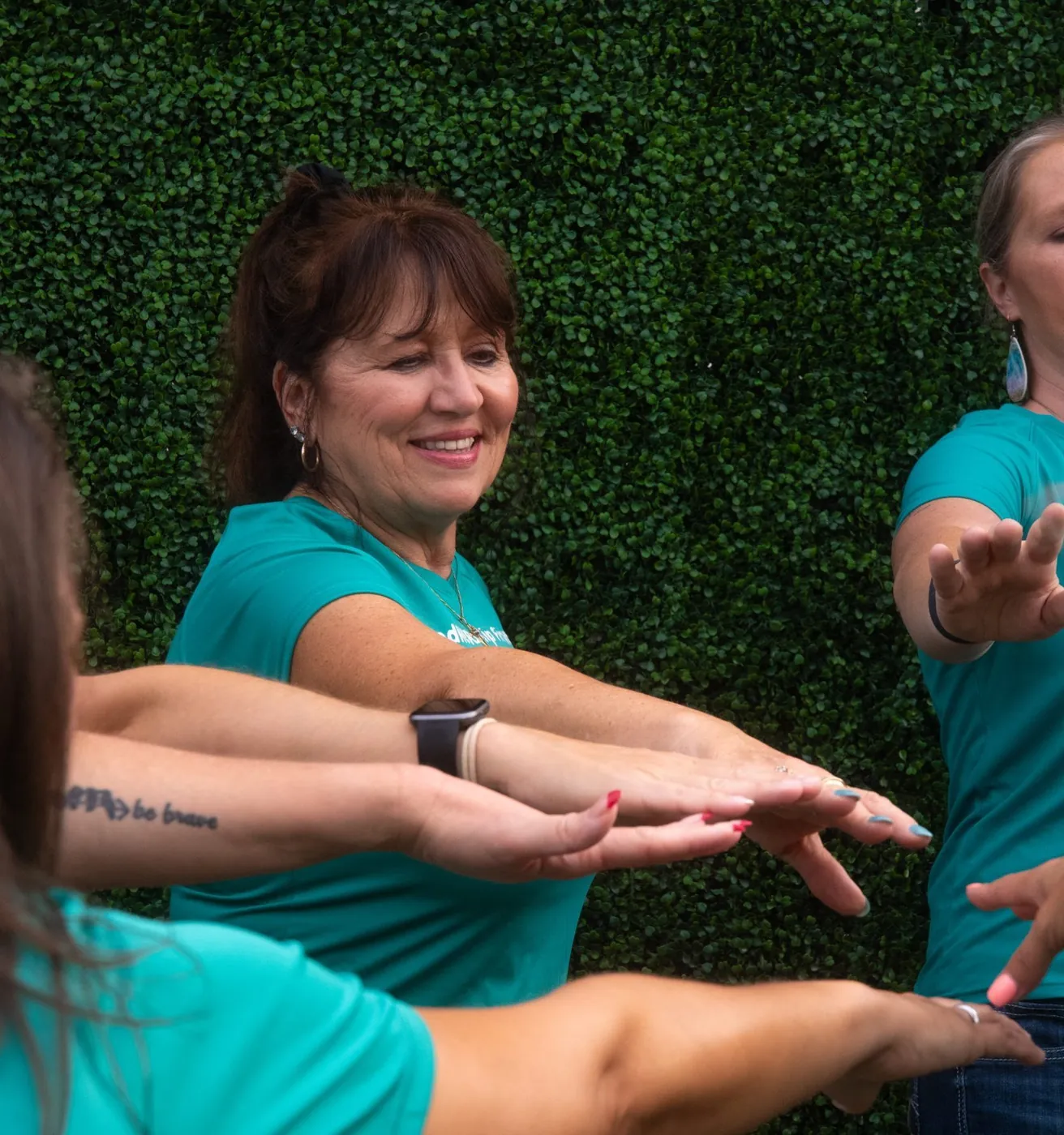 A group in matching teal shirts stretching together
