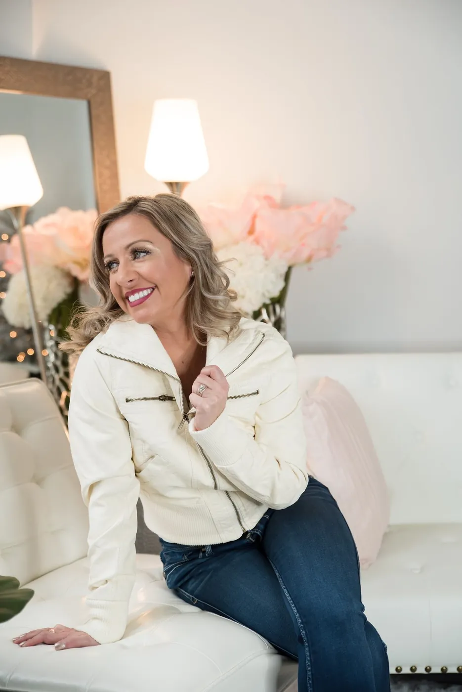 Krystalore Crews seated on a white sofa, smiling warmly