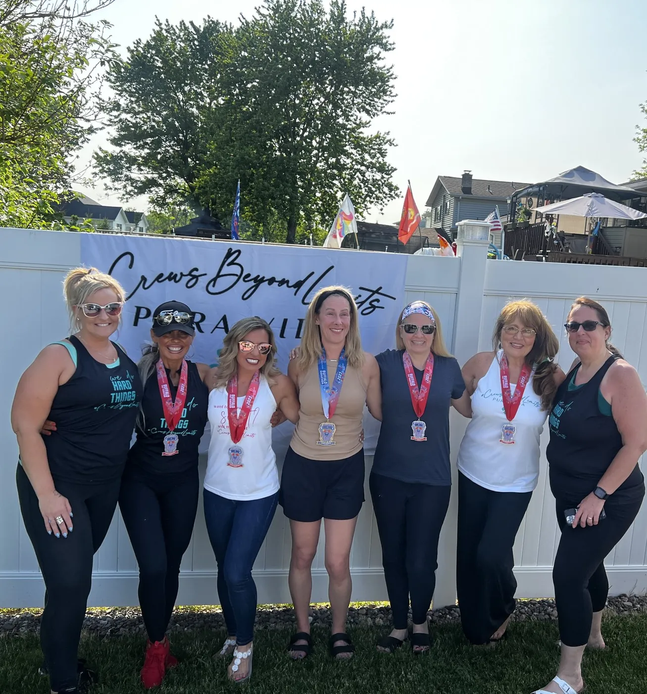 A smiling group of runners with medals in front of a Crews Beyond Limits banner