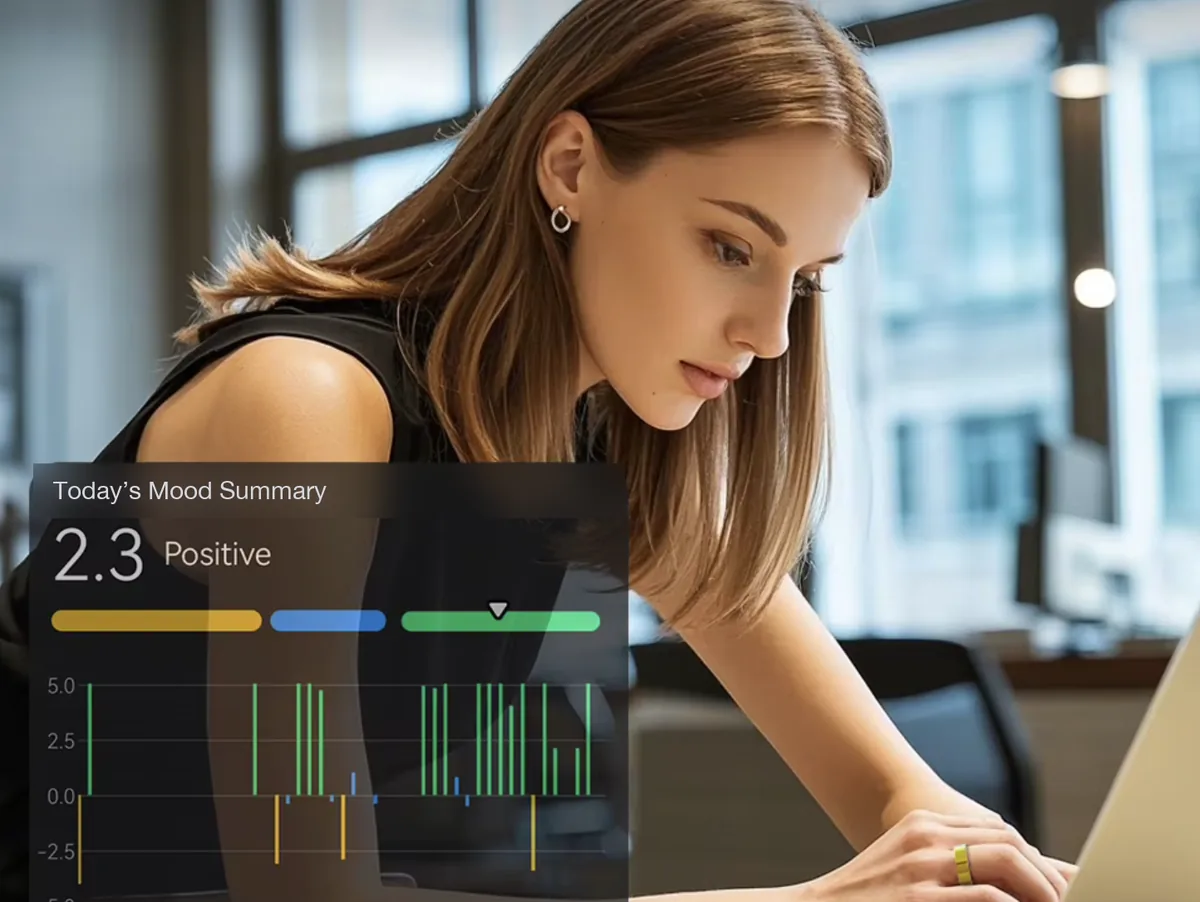 A woman at her laptop wearing a smart ring, with a mood summary showing a positive day